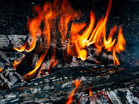Orange flames of fire of a wood fire. The heat of a wood fire. Tourist place in nature in the forest. Cooking on the grill. Background image. Free space for text.