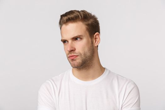 Angry and displeased caucasian bearded blond young man feeling jealous or aggressive towards coworker, look left with contempt or disdain, frowning, pouting offended, standing white background.