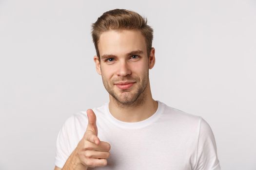 Bang. Close-up shot handsome cheeky and funny blond guy with bristle, blue eyes, pointing finger at camera with finger pistol and smiling, picking, making choice, invite you, white background.