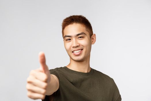 People, different expressions and lifestyle concept. Great idea, nice work. Portrait of enthusiastic asian male student found good part-time jow, recruit young people apply for job, show thumbs-up.