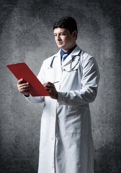 Doctor with tablet for documents, scans documents against the background of the wall