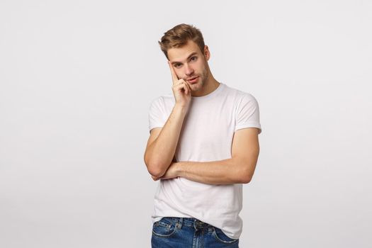 Annoyed and fed up young tired blond guy listening uninteresting boring talk, looking away distant with thoughtful, confused expression, lean on hand, thinking, space out, white background.
