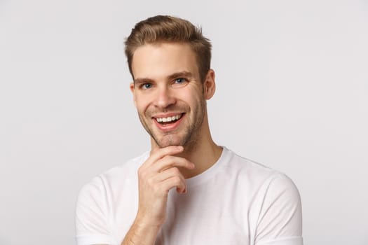 Very good. Intrigued and pleased thoughtful young man, smiling satisfied nod in agreement, touching chin, agree with friend, made-up good plan, give approval, standing white background.