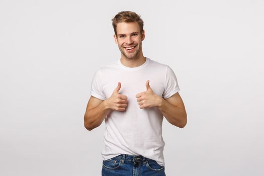 Nice job, congratulations. Happy and satisfied good-looking blond guy with bristle show thumbs-up in approval, like or recommendation gesture, smiling pleased, agree, encourage friend made good job.