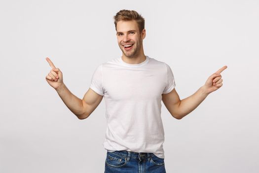 Handsome outgoing smiling blond caucasian male, laughing carefree and delighted, have large opportunities, two ways or choices, pointing sideways, give advice, show left and right product promo.