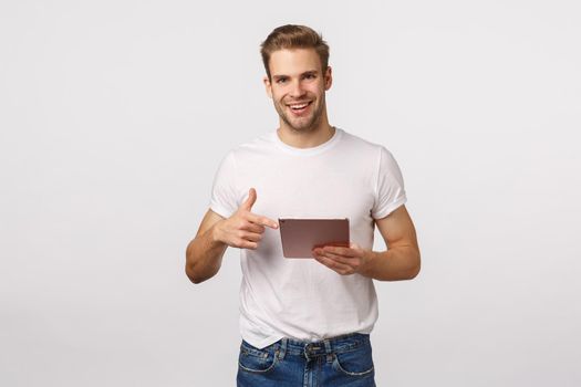Man asking if friend already read article, holding digital tablet and pointing device, smiling, discuss photo with coworker, making arrangements in plans using app, standing white background.