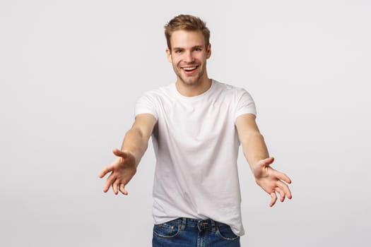 Man suggest lend hand, help out carry something. Joyful charismatic blond guy with bristle, extend hands to catch or hold something, smiling happy, standing friendly white background.