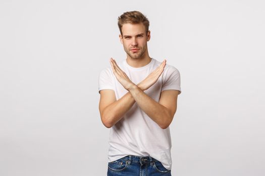 I disagree. Serious-looking blond guy with bristle making cross, stop gesture over chest and looking assertive camera, protest, give negative feedback, prohibit action, dont agree, white background.