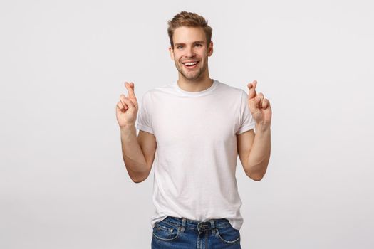 Man having high hopes. Enthusiastic lucky attractive blond guy, cross fingers for good luck, hopefully smiling and looking up, relish sign good deal, anticipate good news, white background.