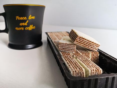 Coffee mug standing on white table and box of small nut wafers