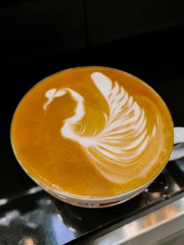 Swan latte art on cafe latte on dark stone table