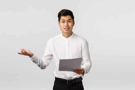 Skeptical and displeased asian male entrepreneur complaining unsatisfied with received documents, shrugging extend hand sideways in dismay, frowning upset, talking to employees.