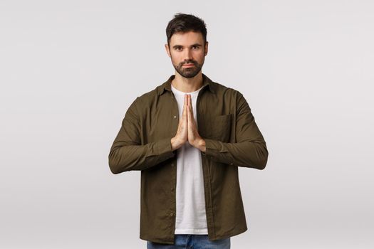 May the force be with you. Confident and patient good-looking bearded man practice yoga, press palms together in namaste, praying gesture smiling peaceful and relaxed, meditating, bowing politely.