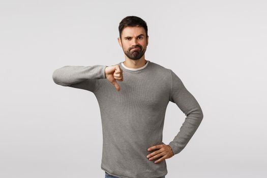 Very bad, dont approve. Skeptical and judgemental serious bearded male entrepreneur left unamused watching awful, disappointing show, make thumb-down, smirk unsatisfied, white background.