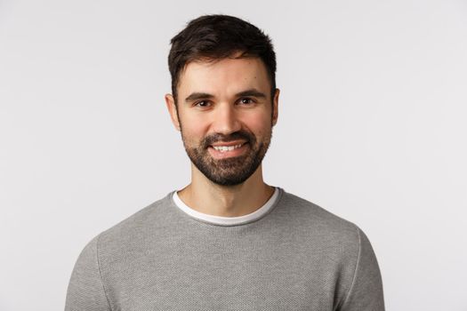 Motivated cheerful and glad, pleasant caucasian adult bearded man in grey sweater, smiling with delighted expression, looking excited and satisfied, nod agreement, give approval, white background.