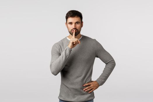 Shhh, its secret. dont tell anyone. Mysterious charming and kind young bearded dad asking keep quiet, shushing with index finger pressed to lips, seal mouth, tell be silent, white background.