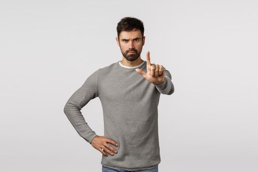 Stop right here. enough. Serious-looking determined and confident bearded male friend warn partner, extend index finger and shaking it in restriction, forbid, prohibit action, stand white background.