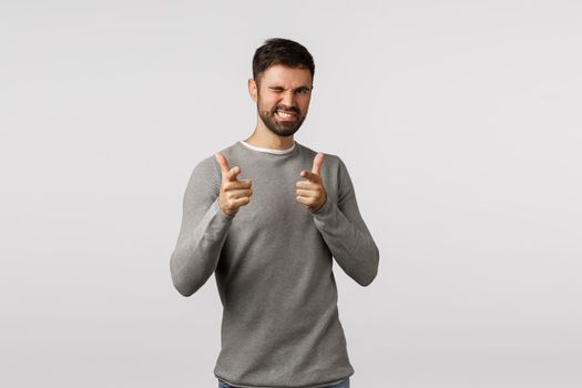 You rock man. Attractive and cheeky, confident bearded man, pointign finger pistols camera and wink as congratulating friend made good deal, praise amazing work, smiling satisfied, white background.