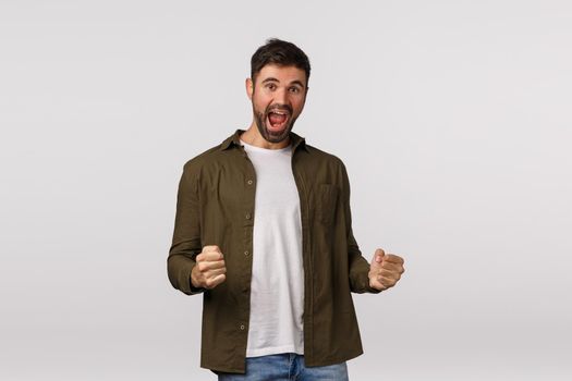 Guy made good deal feeling upbeat. Excited happy bearded male fist pump, cheering or rooting, feeling ecstatic, dancing achieve goal, celebrating victory, lottery winner, white background.