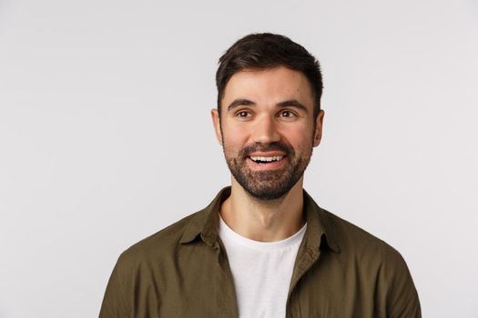 Guy check out interesting event, looking pleased with satisfied smile. Attractive bearded man in coat over t-shirt, looking left and smirking delighted, watching impressive performance.
