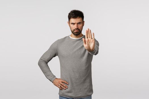 Serious and assertive bearded man trying prevent accident happen, restrict or warn, pull back, extend arm in stop gesture, frowning angry and confident, prohibit or forbid action, white background.