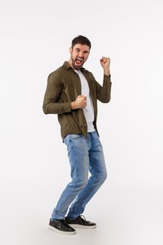 Achievement, goal and win concept. Full-length vertical shot cheerful handsome successful businessman in casual outfit, dancing triumphing and celebrating victory, become champion, fist pump.