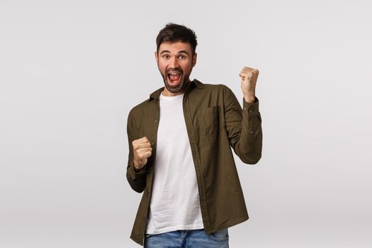 Relish, celebration and victory concept. Cheerful triumphing lucky businessman, guy winning, achieve prize or goal, have great news, fist pump and smiling, become champion, white background.