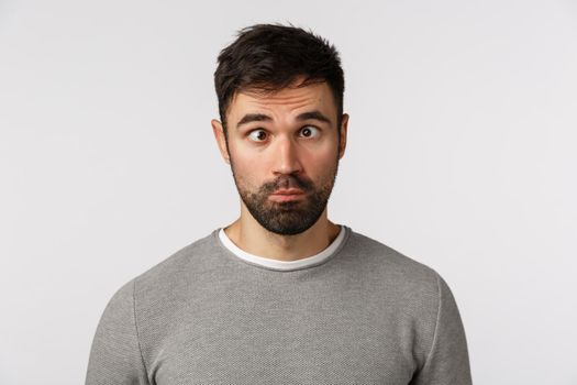 Emotions, people concept. Funny and goofy cute bearded guy making crazy eyes, squinting and grimacing, pouting, standing playful, trying make friends laugh, standing white background.