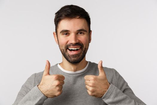 Close-up studio pleased, satisfied good-looking bearded male friend show thumbs-up in approval, like or accept gesture, recommend product, satisfied with device or company service, white background.