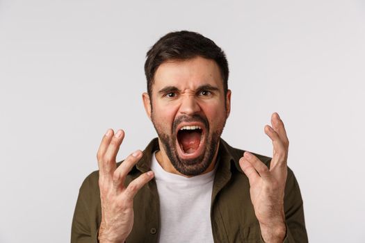 Man losing temper feeling aggression and depression. Distressed and bothered bearded male fed up, tired of arguing shouting, shaking hands aggressive and cursing someone, look angry, white background.