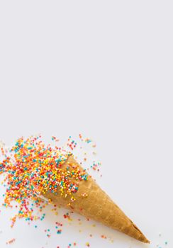 Ice cream in a waffle cone covered with bright sprinkles with space for text