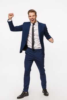 Vertical full-length shot excited, rejoicing cheerful businessman in classic suit, raising hands up, fist pump celebrating victory, become champion, made good deal, signed contract, white background.