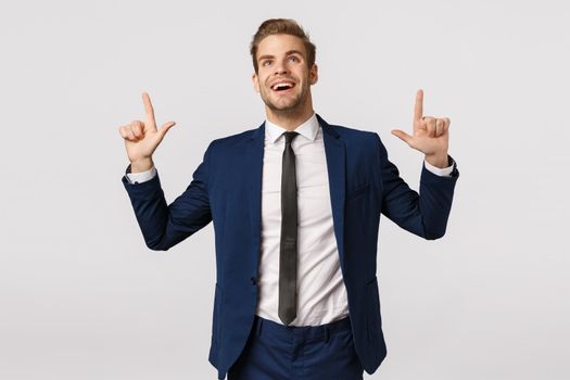 Dreamy, optimistic businessman seeing prosperity chance, smiling and looking up excited, contemplate beautiful scenery, captured attention on product promo, standing glad white background.