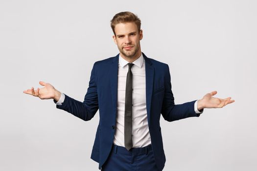 I dont know. Unsure and puzzled handsome businessman with bristle, blond haircut, wear suit, spread hands sideways and shrugging uncertain, have doubts about client, frowning perplexed.