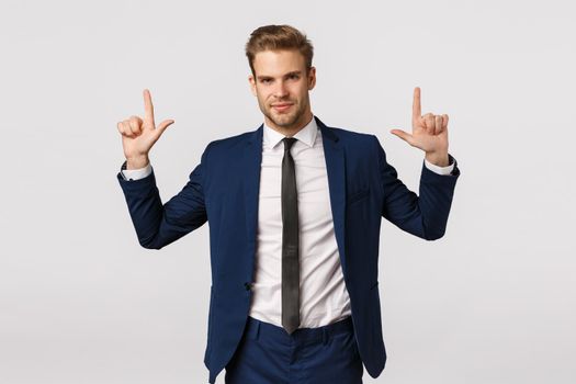 Confidence, business and corporate concept. Attractive young bearded businessman, man in suit, pointing up and smiling camera with assertive look, know what you searching, give advice.