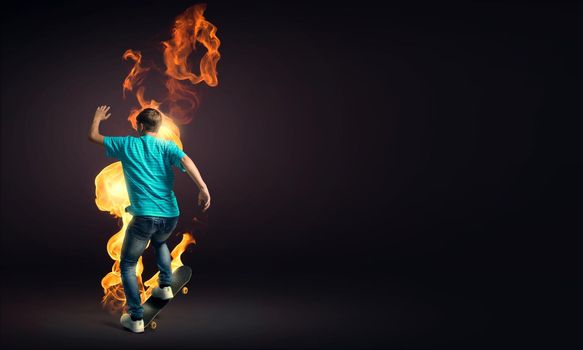 Skater boy riding on his skateboard burning in fire