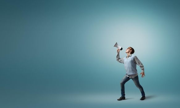 Teenager boy in glasses screaming emotional in megaphone