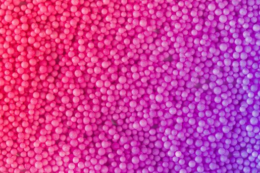 Many pink and violet little balls for children playground. Cosmetics powder. Candy sprinkles. Top view. Trendy absract background or backplate for your design. Color 2022