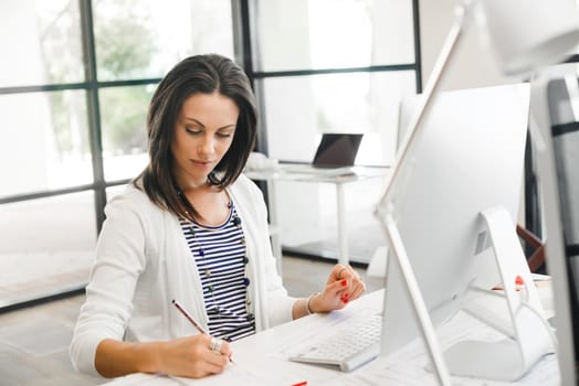Attractive brunette woman at office desk work on computer