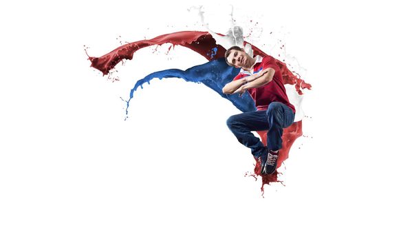 Young male dancer in jump on white background with colorful paint plashes