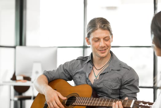 Young man playing guitar and attractive woman enjoying it