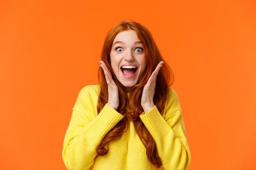 Excitement, emotions and holidays concept. Waist-up shot cheerful impressed and excited redhead woman screaming from thrill and joy, hold hands near face, open mouth and glance amazed.
