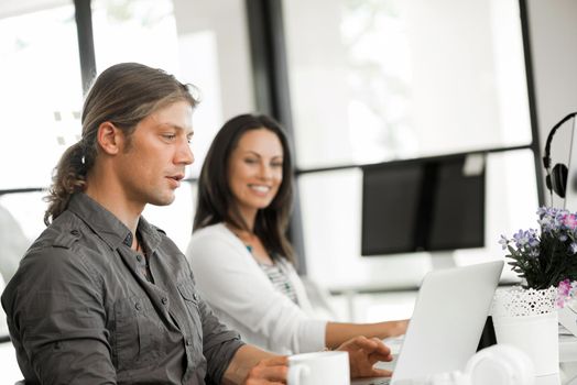 Young coworkers working together and discussing points while using computer