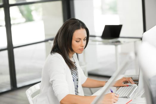 Attractive brunette woman at office desk work on computer