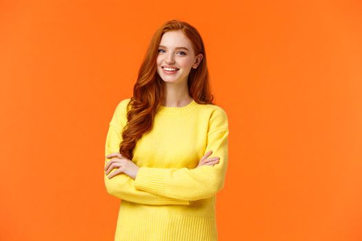 Business, e-commerce and people concept. Modern student, redhead girl learn IT, digital design in college, cross arms over chest with confident, assertive posture, smiling happy, orange background.