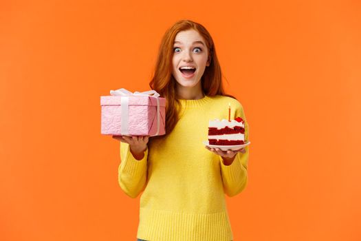 Surprised happy and amused cheerful redhead b-day girl celebrating her birthday receive presents and sweets, look amused and dreamy, gasping excited, holding wrapped pink box with gift, birthday cake.