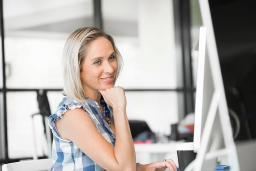 Attractive woman sitting at desk in modern office