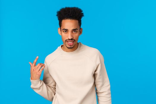 Sassy and confident, self-assured african-american hipster guy acting cool, gesturing pointing himself, looking daring and assertive as if showing hows boss, standing blue background.