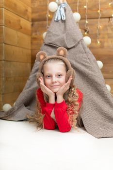 A child in a tent in a red sweater smiles lying in headphones hat New Year's studio wheel park sky entertainment, carnival festival round turn, recreational. Traditional construction fairground, life tourism attraction