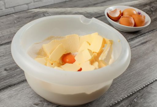 Plastic bowl with butter, egg yolk and flour to be mixed. Cake preparation